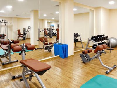 Gimnasio moderno con equipo de ejercicio y pesas en una habitación luminosa.