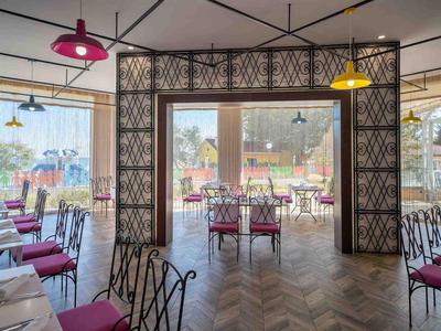 Área de comedor moderna y luminosa con lámparas colgantes coloridas y sillas con cojines rojos