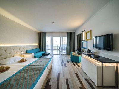 Chambre d'hôtel moderne avec lit double, TV, balcon et vue sur la mer.