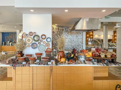 Buffet avec divers plats et assiettes décoratives au mur dans un restaurant d'hôtel.