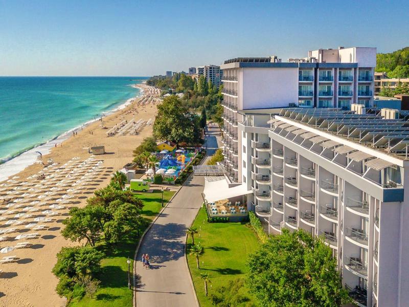Hôtel surplombant une longue plage de sable avec des parasols et une mer turquoise