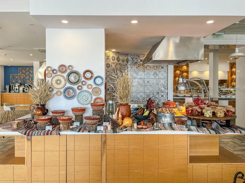 Buffet avec divers plats et assiettes décoratives au mur dans un restaurant d'hôtel.