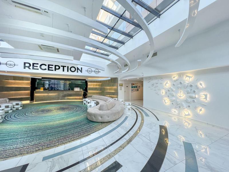 Hall d'hôtel moderne avec réception courbée, espace d'accueil et éclairage mural décoratif.