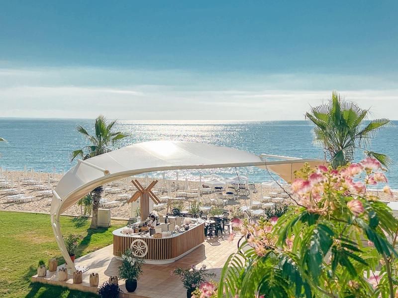 Bar de plage en forme de bateau en bois avec parasols et mer en arrière-plan