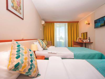 Hotelkamer met twee eenpersoonsbedden, kleurrijke kussens, bureau en aan de muur gemonteerde tv.