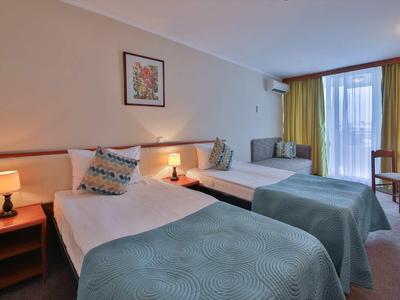 Gezellige hotelkamer met twee bedden, nachtkastjes met lampen en een raam met gordijnen.