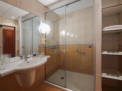 Moderne badkamer met glazen douche, witte wastafel en open plank met handdoeken.