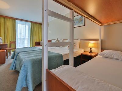 Hotelkamer met twee eenpersoonsbedden, bureau en raam met groene gordijnen.