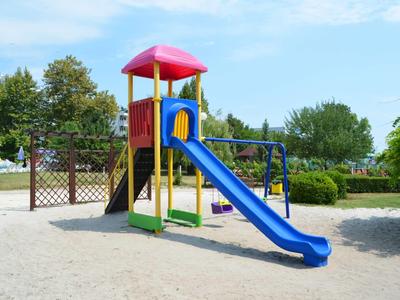 Kleurrijke speeltuin met glijbaan en schommels in een zonnig park.
