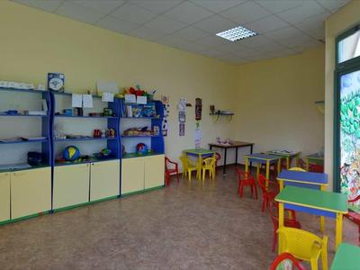 Kinderenkamer met kleurrijke stoelen en kasten, grote deur met kleurrijk glas-in-lood.