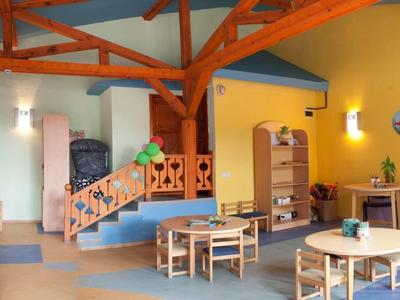 Kleurrijke speel- en eetruimte voor kinderen met kleine tafels en stoelen in een hotel.