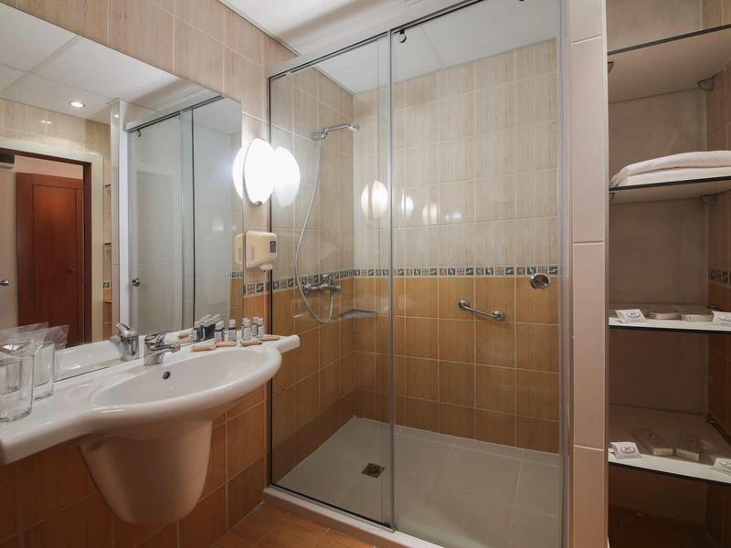 Moderne badkamer met glazen douche, witte wastafel en open plank met handdoeken.