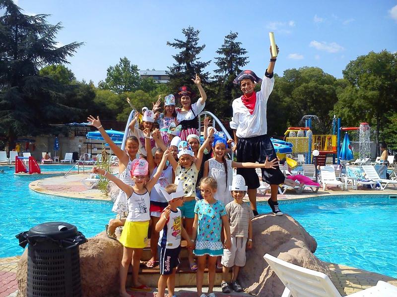Kinderen en volwassenen vieren bij het zwembad met piratenkostuums en attributen.
