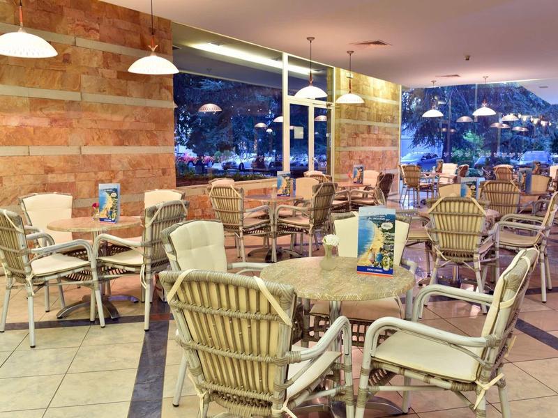 Gezellig hotelzitgedeelte met rieten stoelen en tafels, zichtbaar buiten bij schemering.