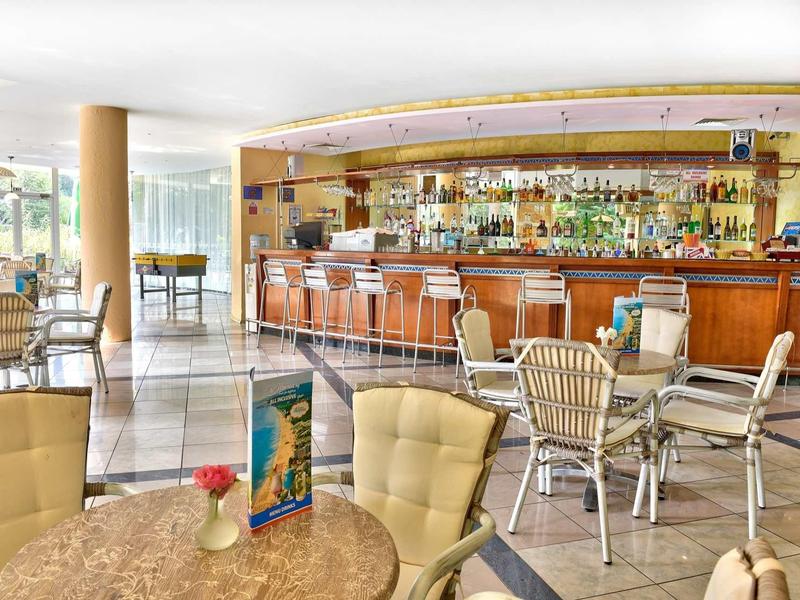 Lichte hotelbar met gestoffeerde stoelen en grote spiegel achter de bar.