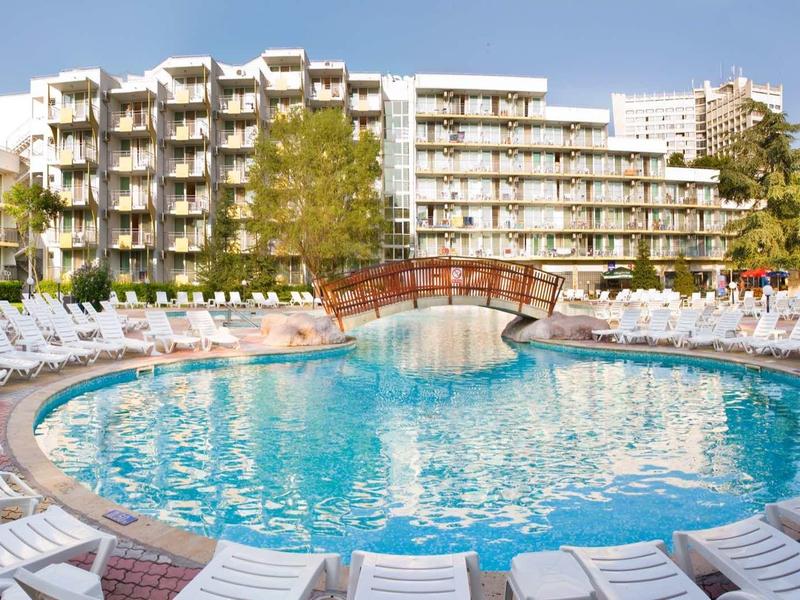 Hotel met groot zwembad en vele witte ligstoelen eromheen