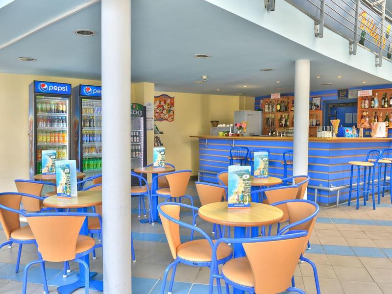 Helder verlichte hotelbar met blauwe en oranje stoelen en tafels