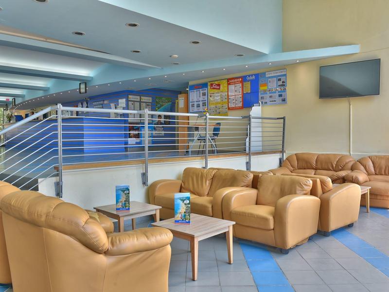 Licht verlichte hotel lounge met comfortabele leren fauteuils en tafels.