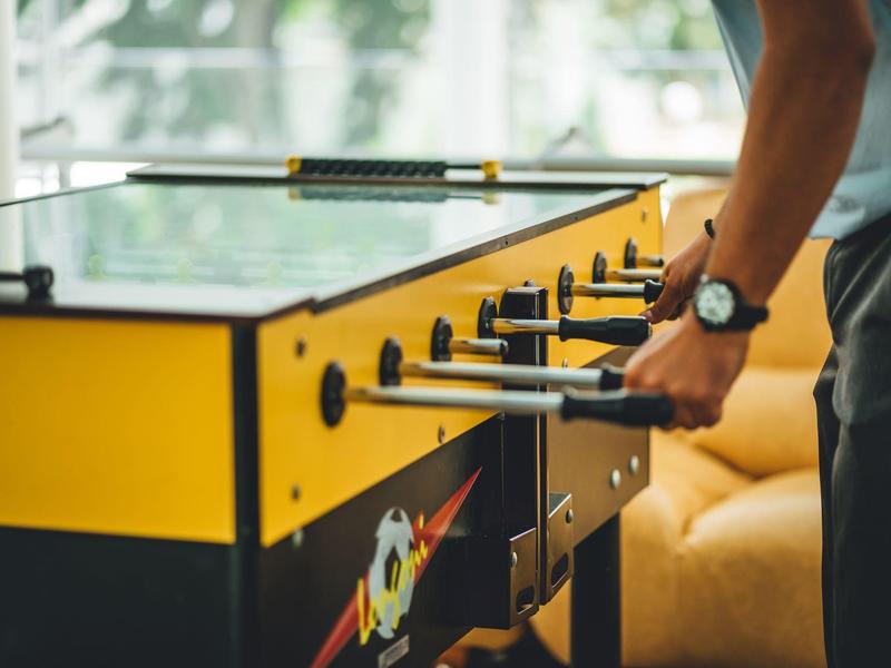 Persoon speelt tafelvoetbal op een gele tafel binnenshuis.