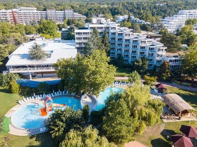 Vista de un hotel con piscina, toboganes de agua y árboles verdes en un complejo vacacional.