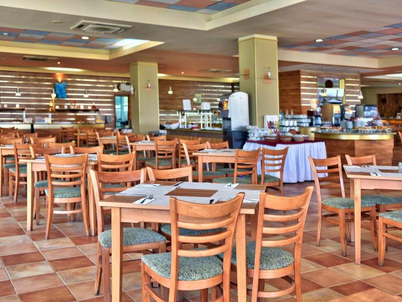 Amplio comedor con sillas y mesas de madera, área de buffet al fondo.