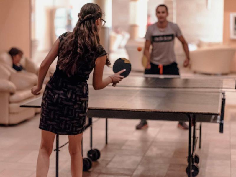 Dos personas juegan al ping-pong en el interior de una casa o hotel.
