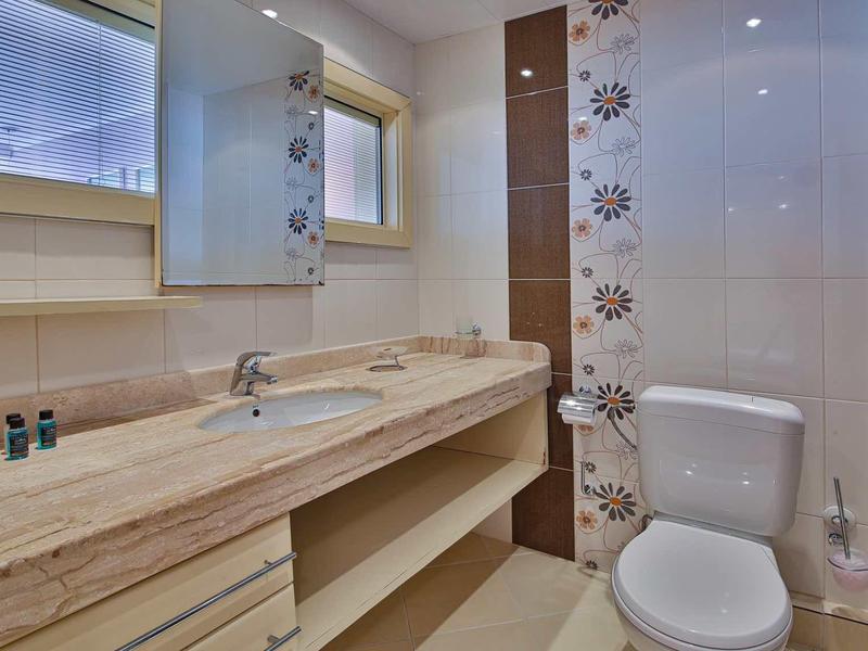 Baño moderno con lavabo de mármol claro y inodoro junto a una pared decorada con patrones.