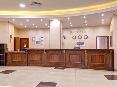 Hotel reception with a long wooden counter and modern lighting.