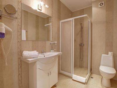 Small bathroom with shower cabin, toilet, sink, and hairdryer.