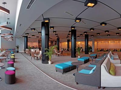 Moderní, prostorný hotelový salonek s barevným sezením a velkými okny.