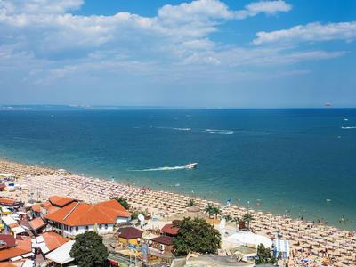 Pláž se slunečními lehátky a modrým mořem pod jasně modrou oblohou