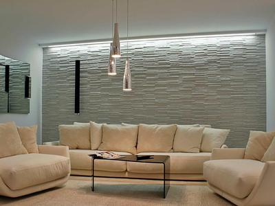 Moderní obývací pokoj s béžovými pohovkami, strukturovaným stěnovým panelem a minimalistickými závěsnými svítidly.