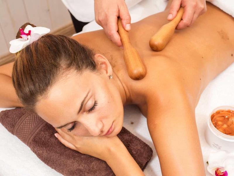 Žena relaxuje při masáži horkými kameny ve wellness centru.