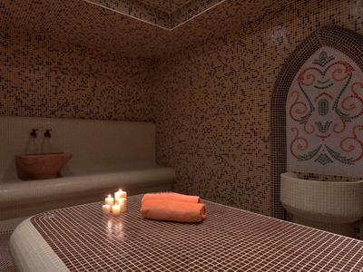 Pohodlná spa místnost s masážním stolem, svíčkami a ručníkem při teplém osvětlení.