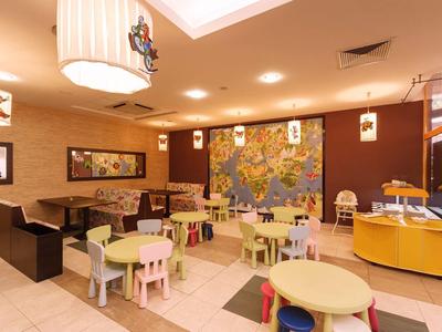 Barevná dětská herna s malými stoly, židlemi a světovou mapou na stěně.