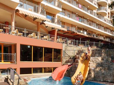 Hôtel à plusieurs étages avec piscine et deux toboggans aquatiques avec des clients s'amusant.