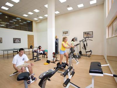 Plusieurs personnes s'entraînent dans une salle de sport lumineuse avec divers équipements.