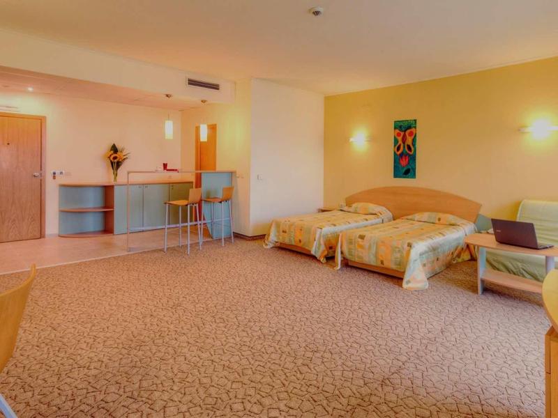 Velký hotelový pokoj se dvěma postelemi, kobercem a posezením.