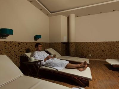 Ein Mann liegt entspannt auf einer Liege in einem ruhigen, braun-beigen Wellnessraum.