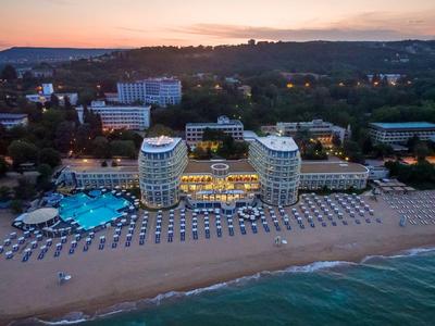 Großer, moderner Speisesaal mit schwarzen Sitzgruppen, weißem Säulendesign und warmem Licht.