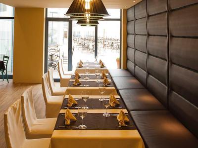 Ristorante moderno con tavoli lunghi, sedie comode e grandi finestre che lasciano entrare la luce del giorno.