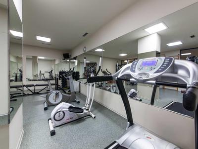 Palestra luminosa con varie attrezzature e grandi specchi sulle pareti.