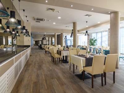 Ristorante luminoso e moderno con pavimento in legno, sedie comode e grandi finestre