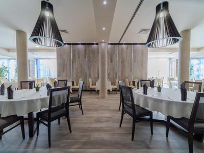 Sala da pranzo moderna con tavoli rotondi e sedie in uno spazio luminoso.