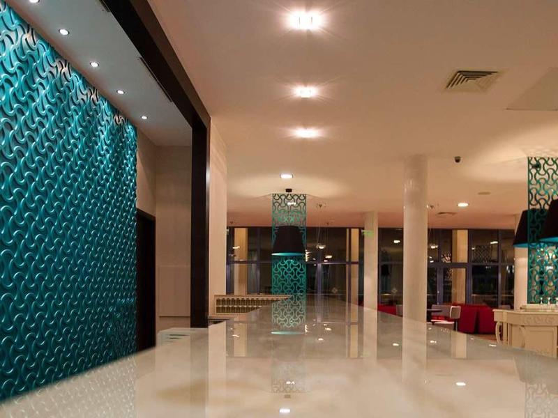 Ein heller, moderner Flur mit glänzendem Boden, türkisfarbener Wand und Deckenbeleuchtung.