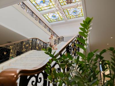 Elegante escalera con techo de vidrio decorativo y plantas verdes en un hotel.