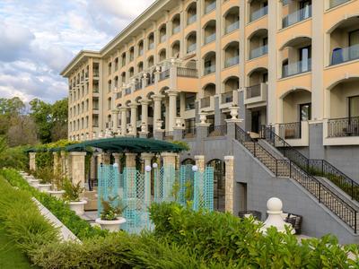 Grande edificio dell'hotel con camere con balcone e una fontana davanti all'ingresso.