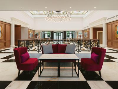 Elegante hall dell'hotel con poltrone rosse e pavimento a scacchiera bianco e nero.