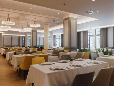 Ristorante moderno con tavoli apparecchiati e sedie comode dai colori chiari.