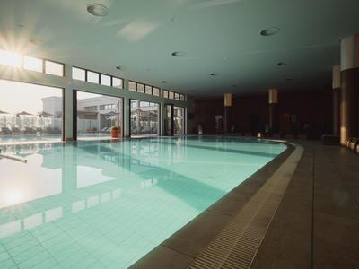 Piscina cubierta luminosa con grandes ventanas y vista al exterior durante el día.